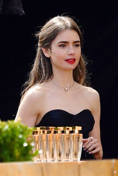 a woman in a strapless black dress holding a stack of glasses with gold ...