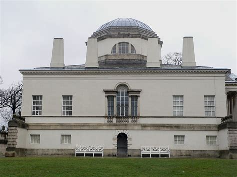 an old building with benches in front of it and a dome on the top floor