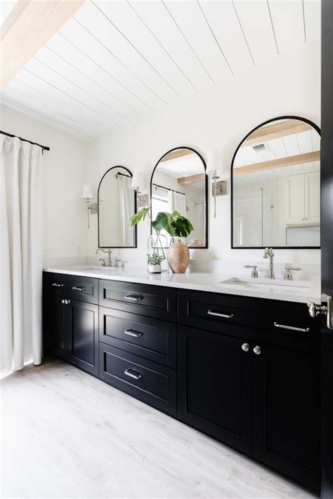 a bathroom with double sinks and mirrors on the wall, along with two large black cabinets