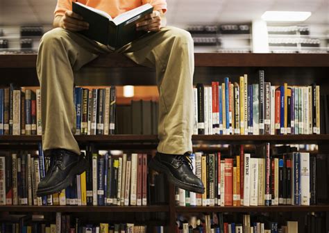 Man Reading Book and Sitting on Bookshelf in Library - Jeet Banerjee