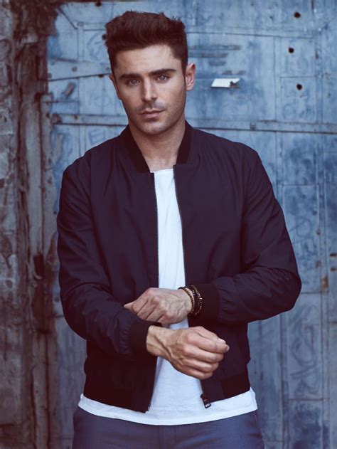 a man standing in front of a wooden door wearing a black jacket and white t - shirt