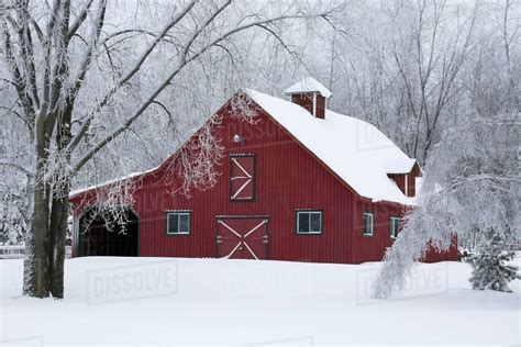 A Red Barn Covered With Snow In Winter; Iron Hill, Quebec, Canada - Stock Photo - Dissolve