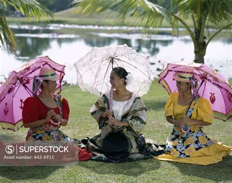 Three young women dressed in traditional costumes sitting together on a ...