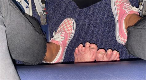 On an airplane, the passenger seated behind her stretches his bare feet ...