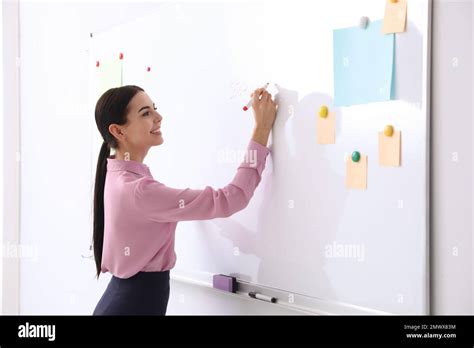 Young teacher writing on whiteboard in classroom Stock Photo - Alamy