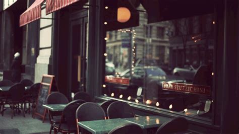 tables and chairs in front of a window with a traffic light on the side walk