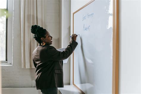 Cheerful teacher writing on whiteboard in classroom · Free Stock Photo