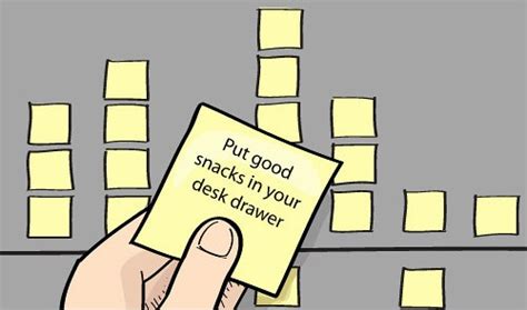 a hand holding a sticky note that says, put good snacks in your desk drawer