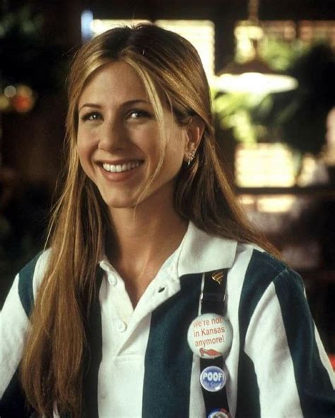 a woman in striped shirt sitting at a table with two badges on her lapel