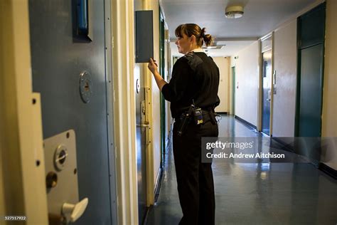 A female prison officer checks on a prisoner through the door window ...