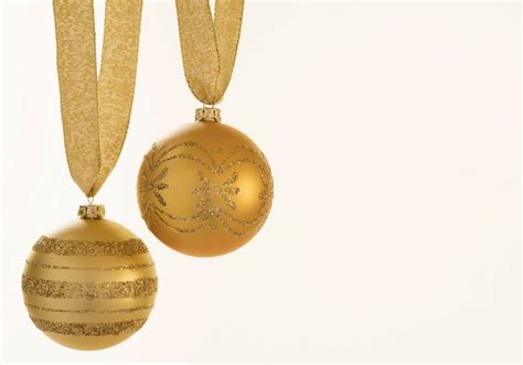 Close-up of gold colored Christmas baubles over white background ...