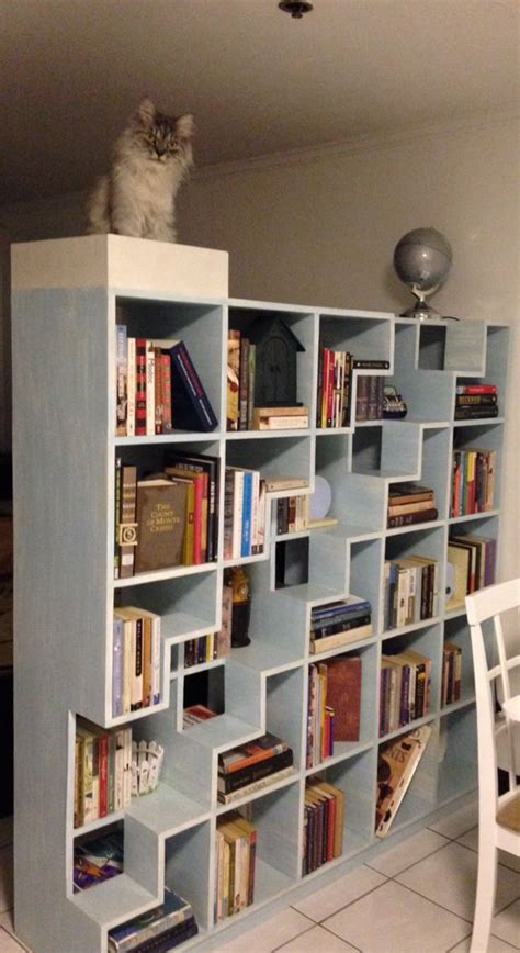 a cat sitting on top of a bookshelf in a room with tile flooring