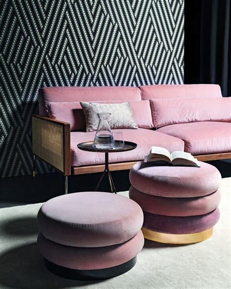 a living room with pink velvet furniture and black wallpaper, including a round coffee table