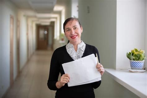 Mujer feliz en el trabajo empleada en el pasillo con un trozo de papel | Foto Premium