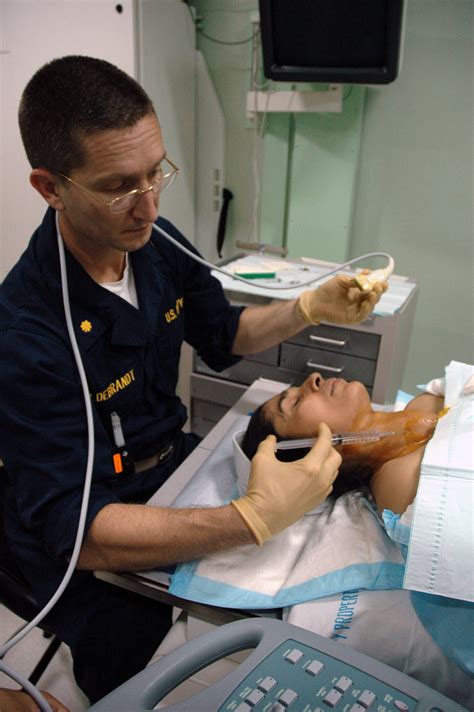 US Navy (USN) LT. CMDR. Kurt Hildebrandt conducts an ultrasound-guided thyroid biopsy on a ...