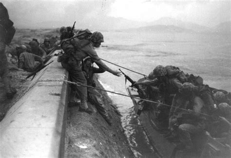 US Marines land from assault craft and climb over the sea defences at ...