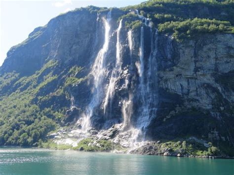 a large waterfall on the side of a mountain next to a body of blue water