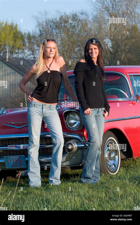 Two young girls beautiful women leaning on a red 1955 Chevy car ...