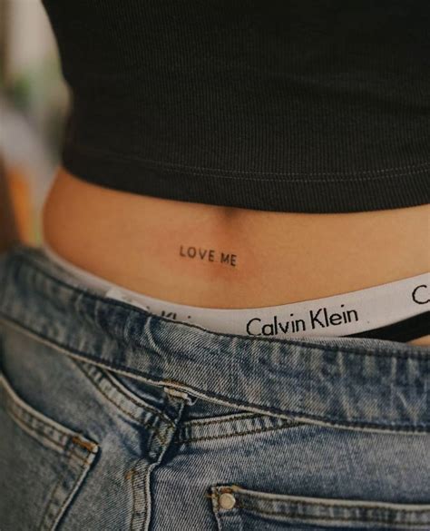 Tattoo that says "love me" located on the lower back.