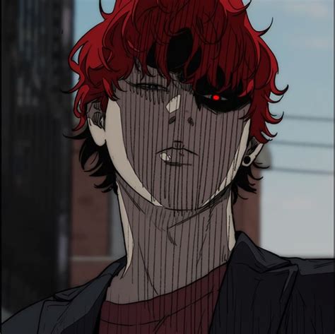 a man with red hair and black eyes stares at the camera while standing in front of a tall building