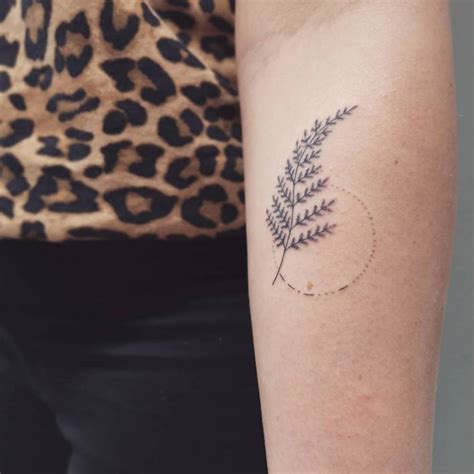 Hand poked fern frond tattooed on the inner forearm.