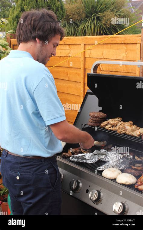 A young man cooking on the bbq Stock Photo - Alamy