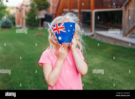 Adorable cute happy Caucasian girl holding Australian flag. Funny child kid covering her face ...