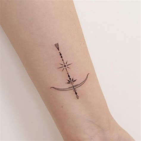 a small tattoo on the wrist of a woman with an arrow and two arrows in it