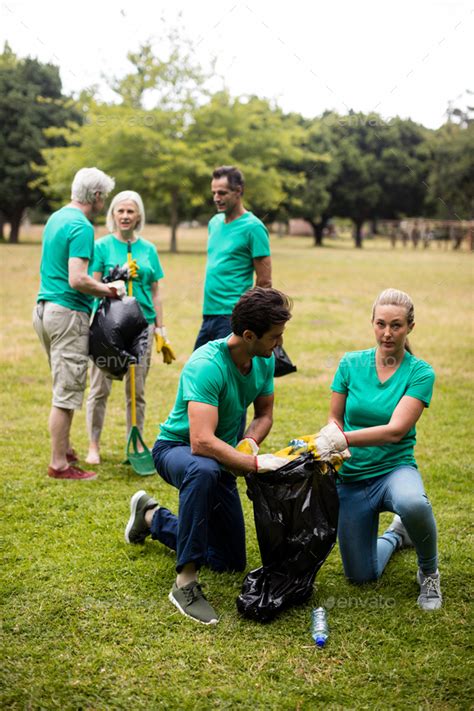 Team of volunteers picking up litter Stock Photo by Wavebreakmedia