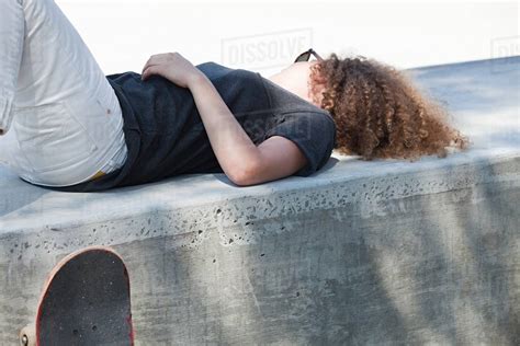 Young woman lying on wall - Stock Photo - Dissolve