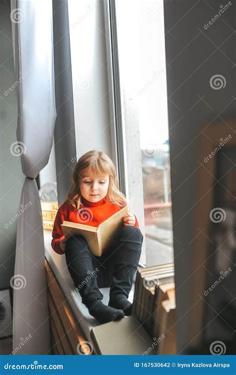 Happy Little Girl Reading Book at Home while Sitting on Window Sill Stock Photo - Image of child ...