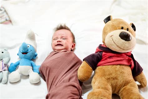 Unhappy baby boy lying between plush toys - Creative Commons Bilder
