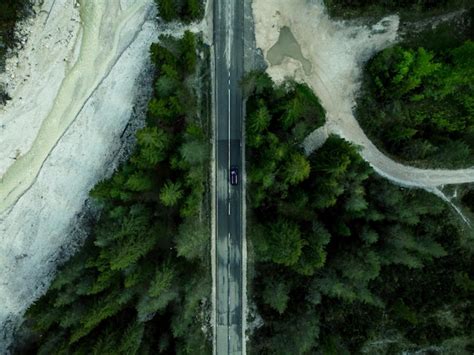 Premium Photo | Car driving on alpine road in forest top down aerial ...