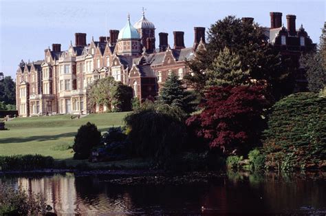 a large building sitting on top of a lush green field next to a lake in ...