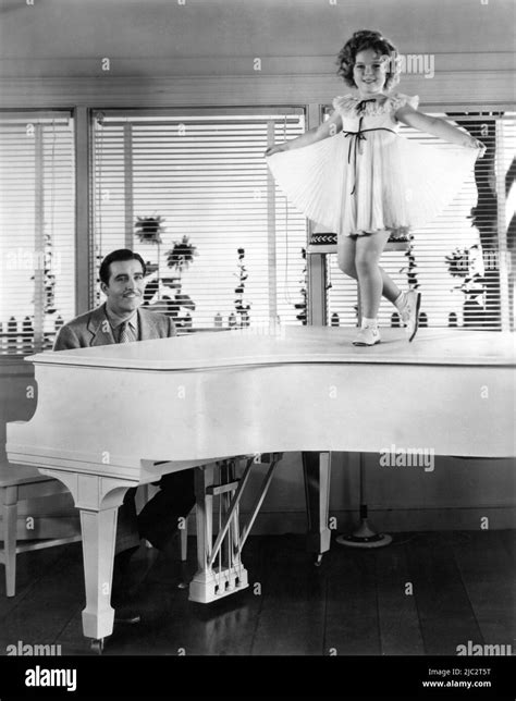 JOHN BOLES at piano with SHIRLEY TEMPLE on set candid dancing on piano during filming of CURLY ...