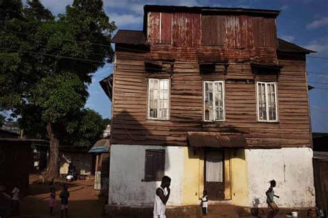 Sierra Leone Architecture: People walk past a traditional colonial-era Board House Traditional ...