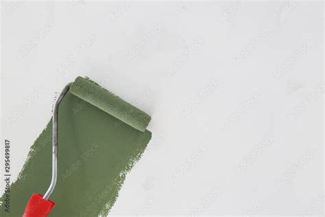 Paint roller. Process of painting with green paint over a white wall. Stock Photo | Adobe Stock