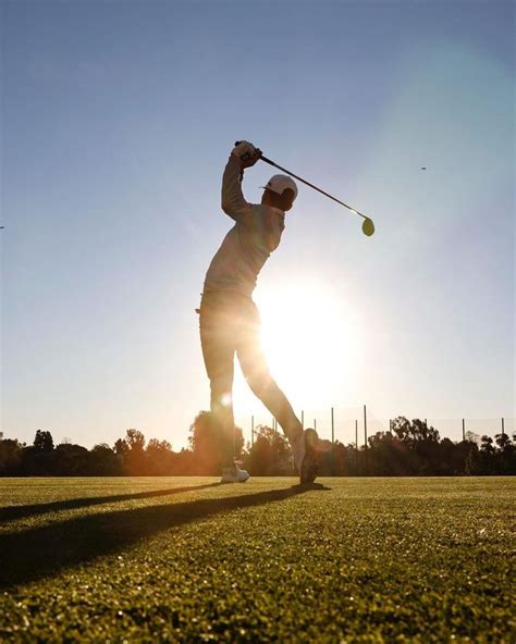 a person swinging a golf club at sunset