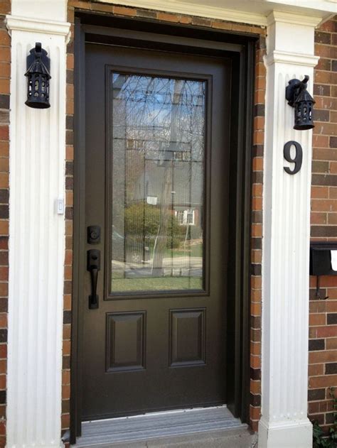 a black front door with two sidelights on brick building and white trim around it