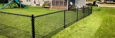 4' black vinyl chain link fence enclosing the backyard of a light tan ...