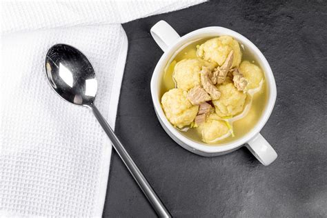 Soup with meat and dumplings on a black background with a white kitchen towel, top view (Flip ...