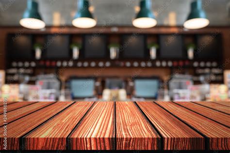 Empty Wooden board top table in front of counter coffee shop blurred background. Perspective ...