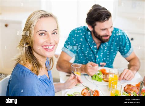 Beautiful young woman sitting at dining table smiling Stock Photo - Alamy
