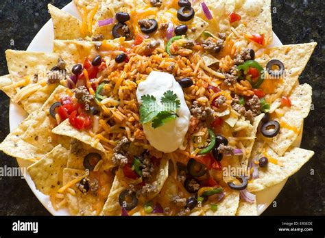 Mexican nachos with sour cream, black olives, ground beef, black beans ...