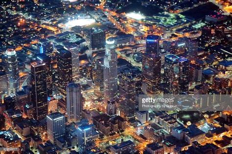 an aerial view of the city at night with lights and skyscrapers in the foreground