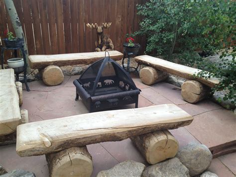 an outdoor fire pit surrounded by logs and benches