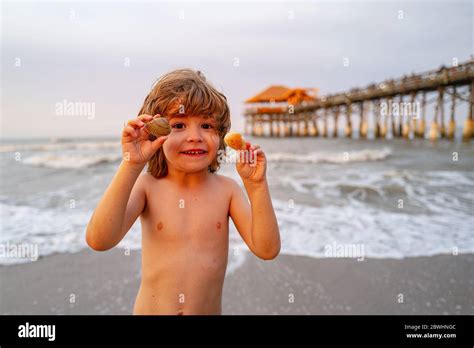 Cute, happy child holding shell at the beach. Cute little boy at tropical beach holding sand ...