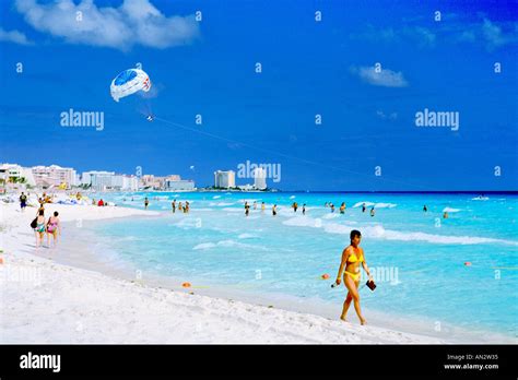 A woman in a yellow bikini strolls along the Cancun beachfront on the Caribbean coast of Mexico ...