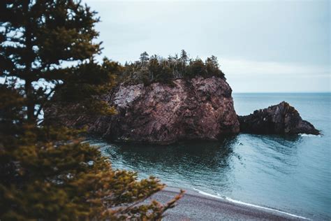 Rocky island and ocean beach on overcast day · Free Stock Photo