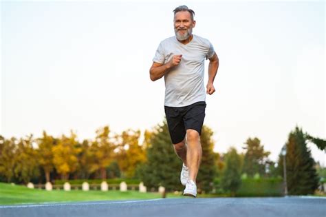 Premium Photo | The smiling happy elderly man running on the road